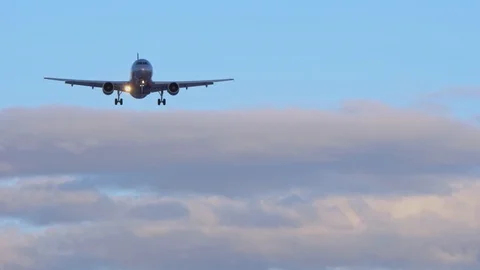 Plane flies in the sky. Close-up. Blue sky, purple clouds in the background. 4K Stock Footage 105700718