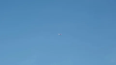 Plane flies through clear blue skies, 4K Stock Footage 111329469