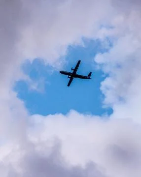 The plane flies through the gray clouds. Stock Photos
