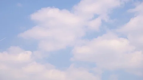 Plane flies through the white fluffy clouds. Jet leaves a trail. 4K, Time Lapse Stock Footage 120760240