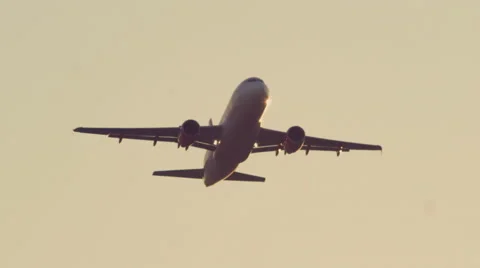 Plane in flight after takeoff ascends into sunset sky coming closer to camera Stock Footage 45388577