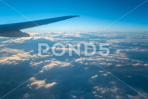 The plane fly in the sky on the background of beautiful clouds Stock Photos