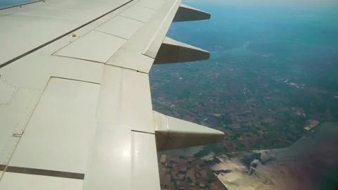 Plane flying above patchwork fields and coastline with visible spoilers. Jet Stock-Footage 335816850