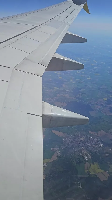 Plane flying above town surrounded by patchy fields Stock Footage 323606972