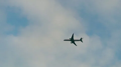 Plane flying across a cloudy blue sky Stock Footage