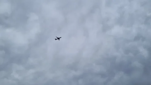 A plane flying against a cloudy gray sky. The concept of transport, travel Stock Footage 252122676