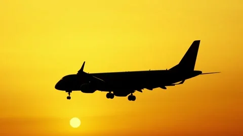 Plane flying against a orange sunset in the evening sky Stock Footage 335458849