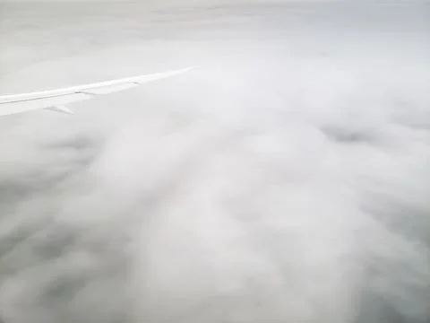 Plane flying high above cloud layer viewed from passenger cabin window Stock Photos