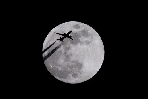 Plane flying in the night sky with the moon in the background. Foto stock