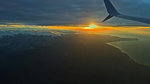 A plane is flying over a beautiful landscape with mountains and a sunset Stock-Footage 277258381