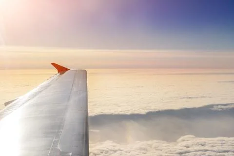 Plane flying over clouds at dawn. Airplane wing over beautiful cloudscape during Stockfoto's