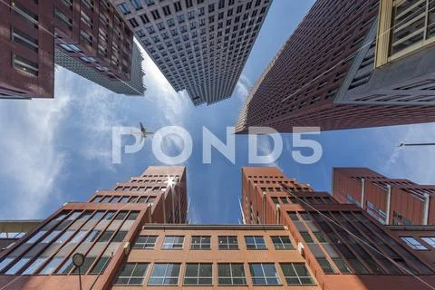 A plane flying over the modern blue cubic buildings located at The Hague city Stock Photos