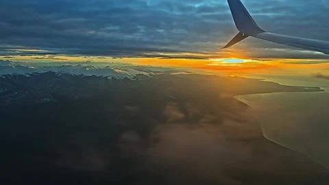A plane is flying over a mountain range and the sun is setting Vidéo 273445261