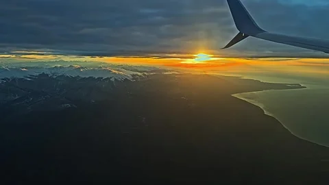 A plane is flying over a mountain range and the sun is setting Vidéo 276719925