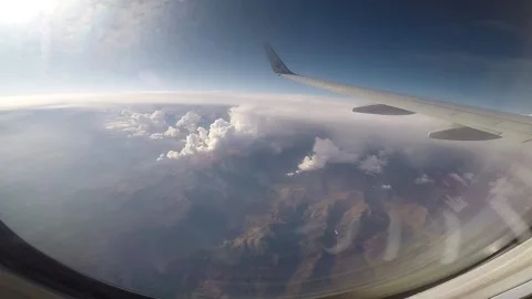 A plane flying over the mountains. High mountains under the clouds. View from Stock Footage