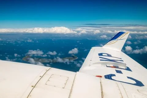 A plane is flying over the ocean with clouds in the sky Stock Photos