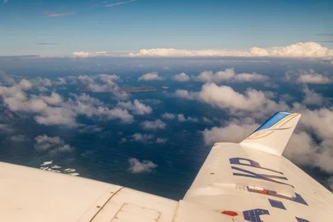 A plane is flying over the ocean with clouds in the sky Stock-Fotos