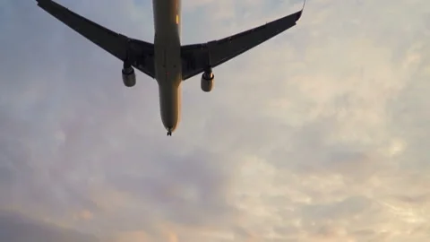 Plane flying overhead in sunset cloudy sky. Aircraft landing in evening slowmo Stock Footage 117376636
