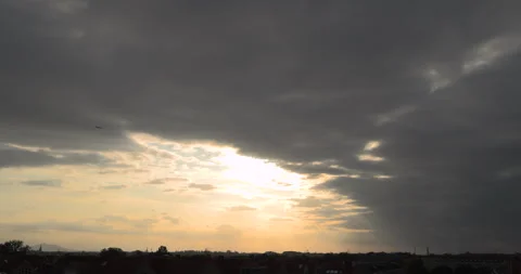 Plane flying past sunlight breaking through dark clouds during sunset. Vídeos de archivo 252948762