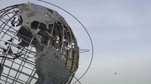 Plane flying by in the sky over Queens NYC, Unisphere globe in Flushing Park Stock Footage 176105804