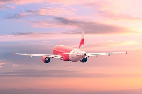 Plane flying in the sunset sky. Stock Photos