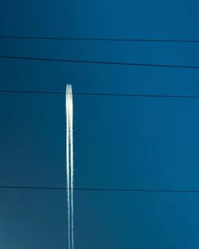 Plane flying through cable lines and leaving white trails Stock Photos