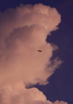 Plane flying through clouds in the sky. Stock Photos