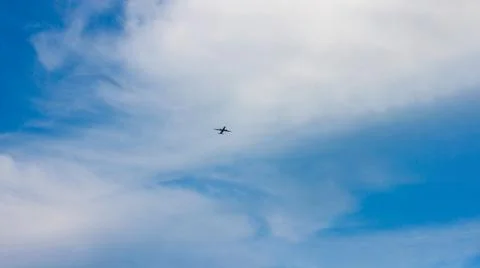 A plane flying through a cloudy blue sky Stock Photos