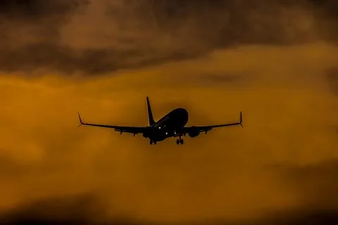 A plane is flying through a cloudy sky at sunset Foto stock