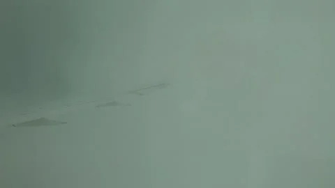Plane Flying Through Fluffy White Clouds, view of wing from porthole Stockbeeldmateriaal 347661344