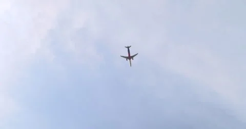 A plane flying through the partly cloudy blue sky Stock Footage 252662508