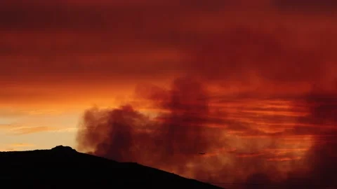 Plane Flying Through Smoke and Sunset to Put Out Fire Stock Footage 137625126