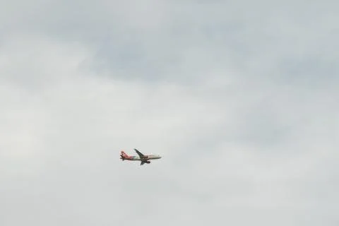 Plane flying under clouds Stock Photos
