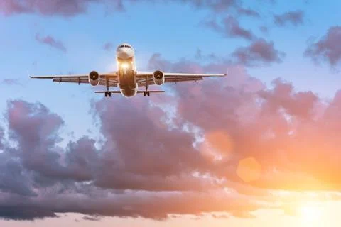 Plane on the glide path before landing on the background of a beautiful sunse Stock Photos