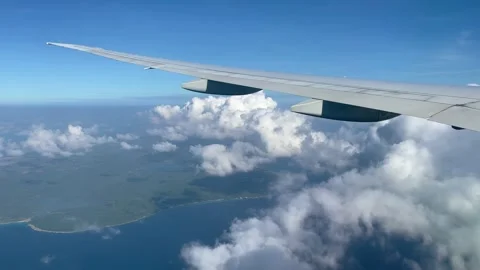 Plane goes through clouds. View from the plane to the island, sea and clouds. Stock Footage 163563027