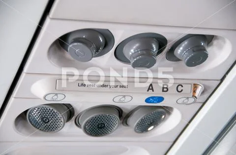 Plane inside interior. Overhead board with sign no smoking and fasten seatbelt Stock Photos