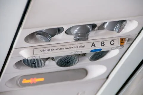 Plane inside interior. Overhead board with sign no smoking and fasten seatbelt Stock Photos