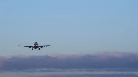 Plane is landing. In background two more aircraft, blue sky purple orange clouds Stock Footage 105700780