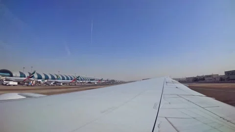 Plane landing at Dubai international airport wing view of emirates flight from Stock Footage 324800749