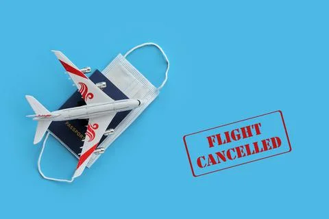 Plane model and face mask on a red background with text flight cancelled. Stock Photos