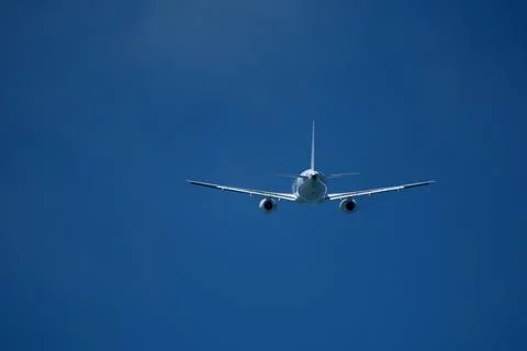 The plane moving away after takeoff. Airplane flying in the blue sky. Stock Photos