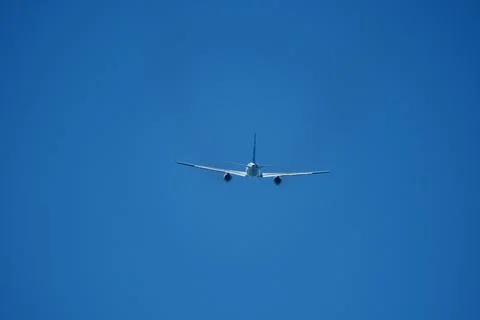 The plane moving away after takeoff. Airplane flying in the blue sky. Stock Photos