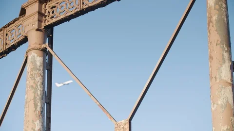 A plane passes behind a close up rusting Victorian gas holder at gasworks in Stock Footage 128918005