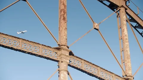 A plane passes from left to right behind a close up rusting Victorian gas holder Stock Footage 128920530