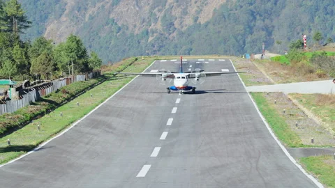 Plane rolling down over runway at mountain small town after landing to airfield Stock Footage 167499110