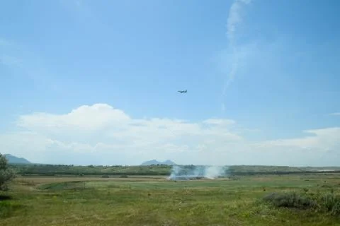 Plane sets up, flying over the field where the dry grass burns Stock Photos