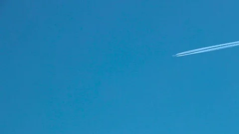 A plane starts creating a white line in the blue sky Stock Footage 85107463