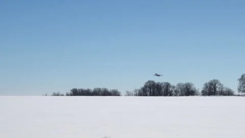 A plane takes off behind the trees in winter. The plane is gaining altitude in Stock Footage 151088584