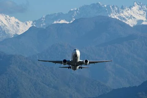 Plane Taking Off with Snow-Capped Mountains in Background Stock Photos