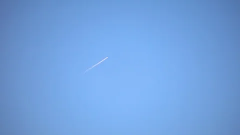 Plane trail in a clear blue sky Stock Footage